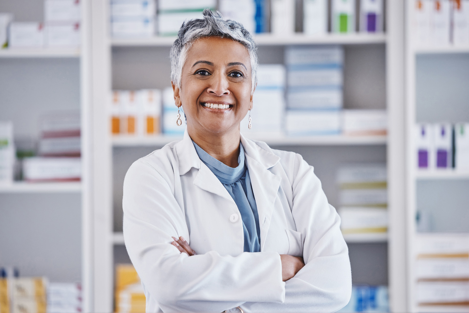 Senior woman pharmacist with arms crossed smiling and looking into camera