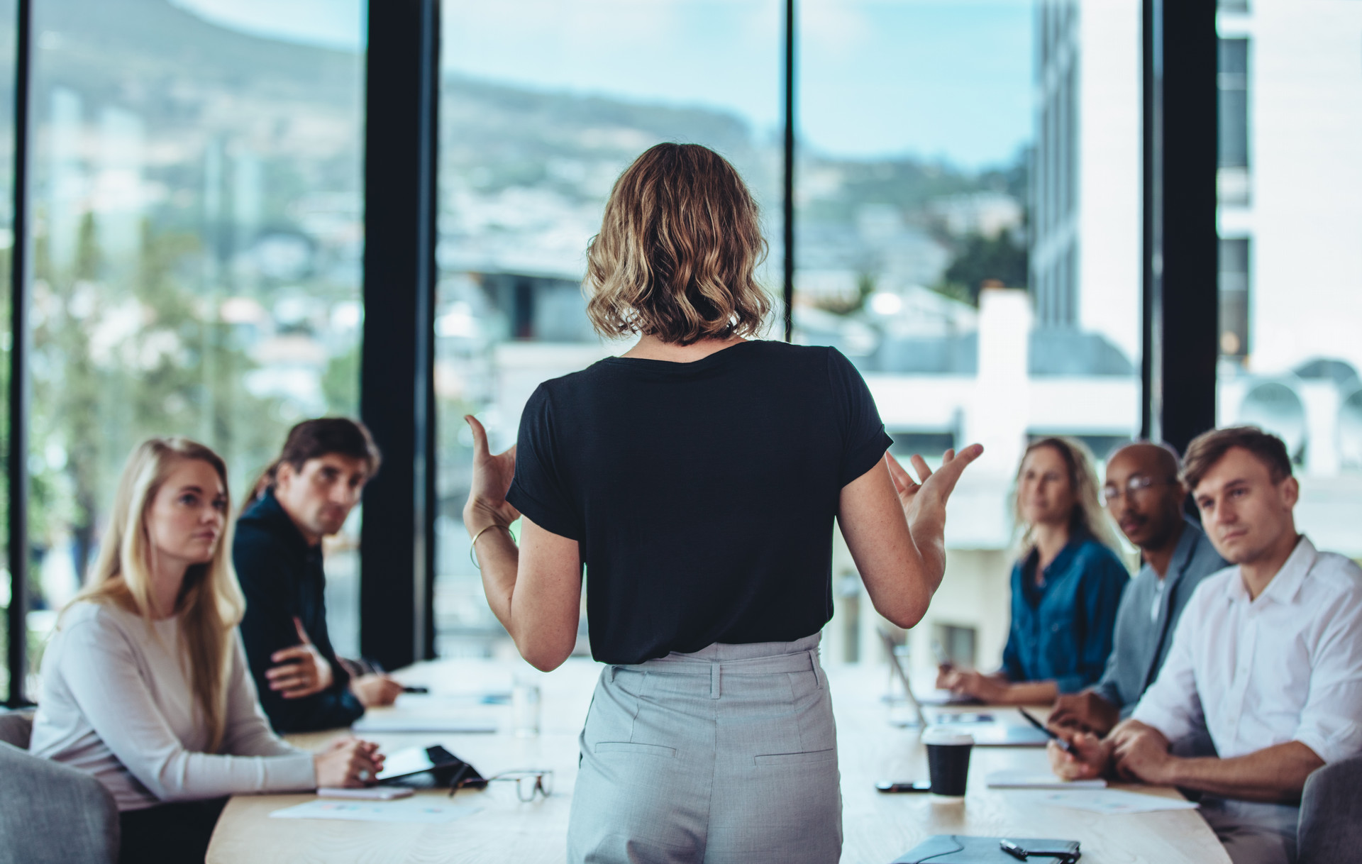 Rear view of a woman explaining new strategies to coworkers during conference meeting in office.