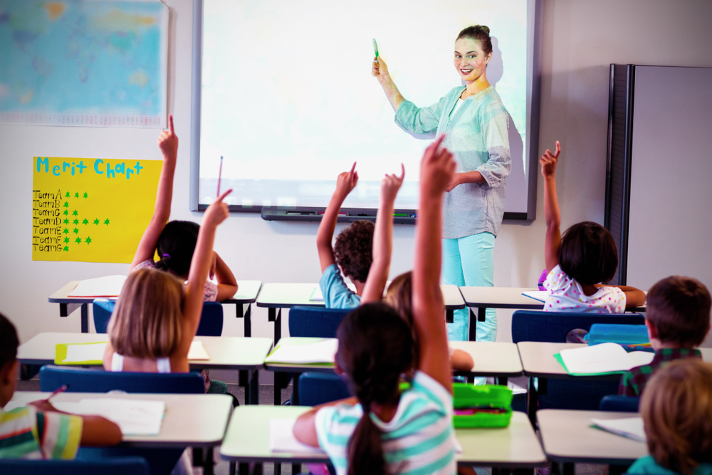Teacher teaching students using projector in classroom at school